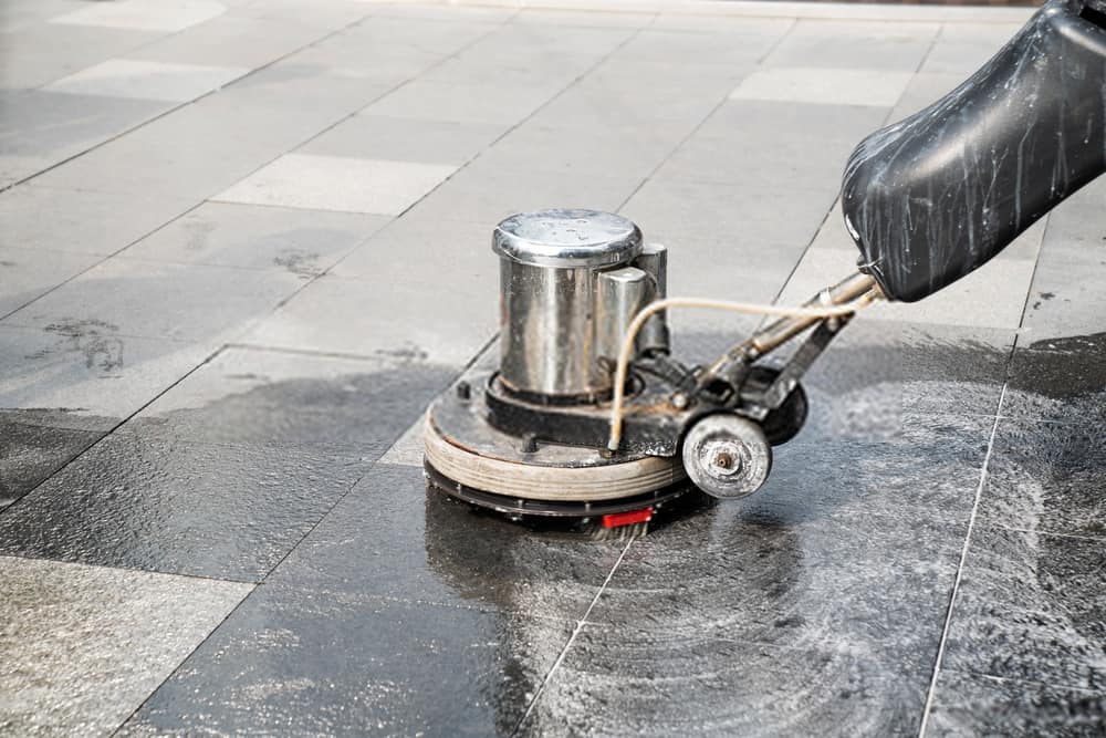 Rotary floor cleaning machine working across a hard floor